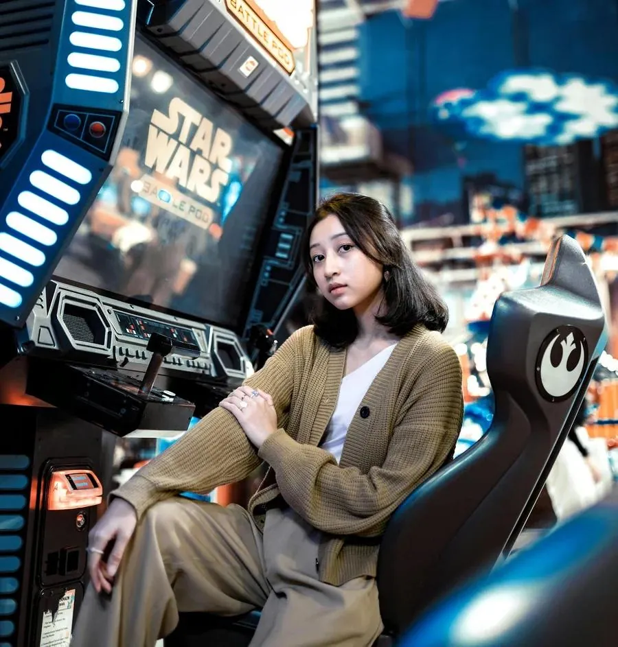 Girl posing in a vibrant arcade, highlighting her gaming passion in a Tinder profile image.