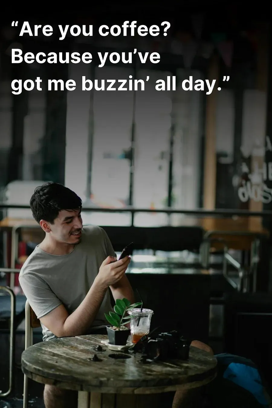Young man laughing at a café after reading a cute pick up line on his phone