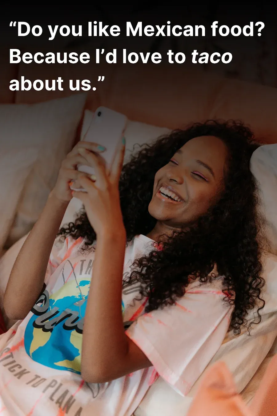 Young woman laughing in bed after reading a funny Tinder pick up line on her phone.