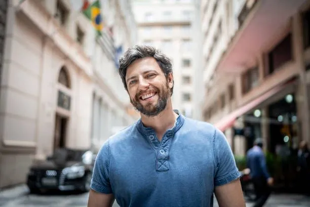 Mann im blauen Hemd lacht breit für ein gutes Dating-Profilfoto