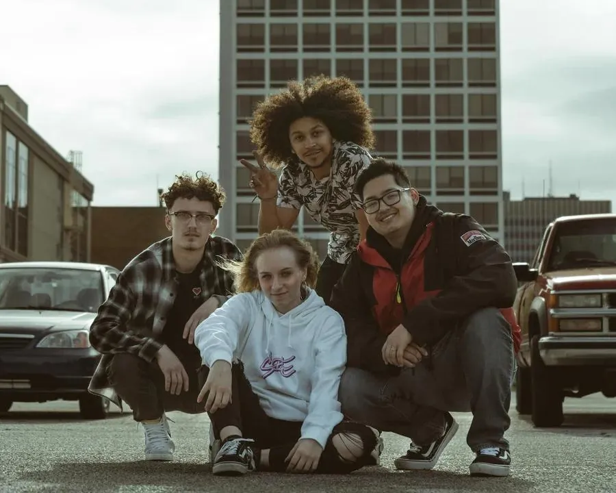 Four young friends posing cheerfully in front of a building, ideal for a Tinder profile picture.